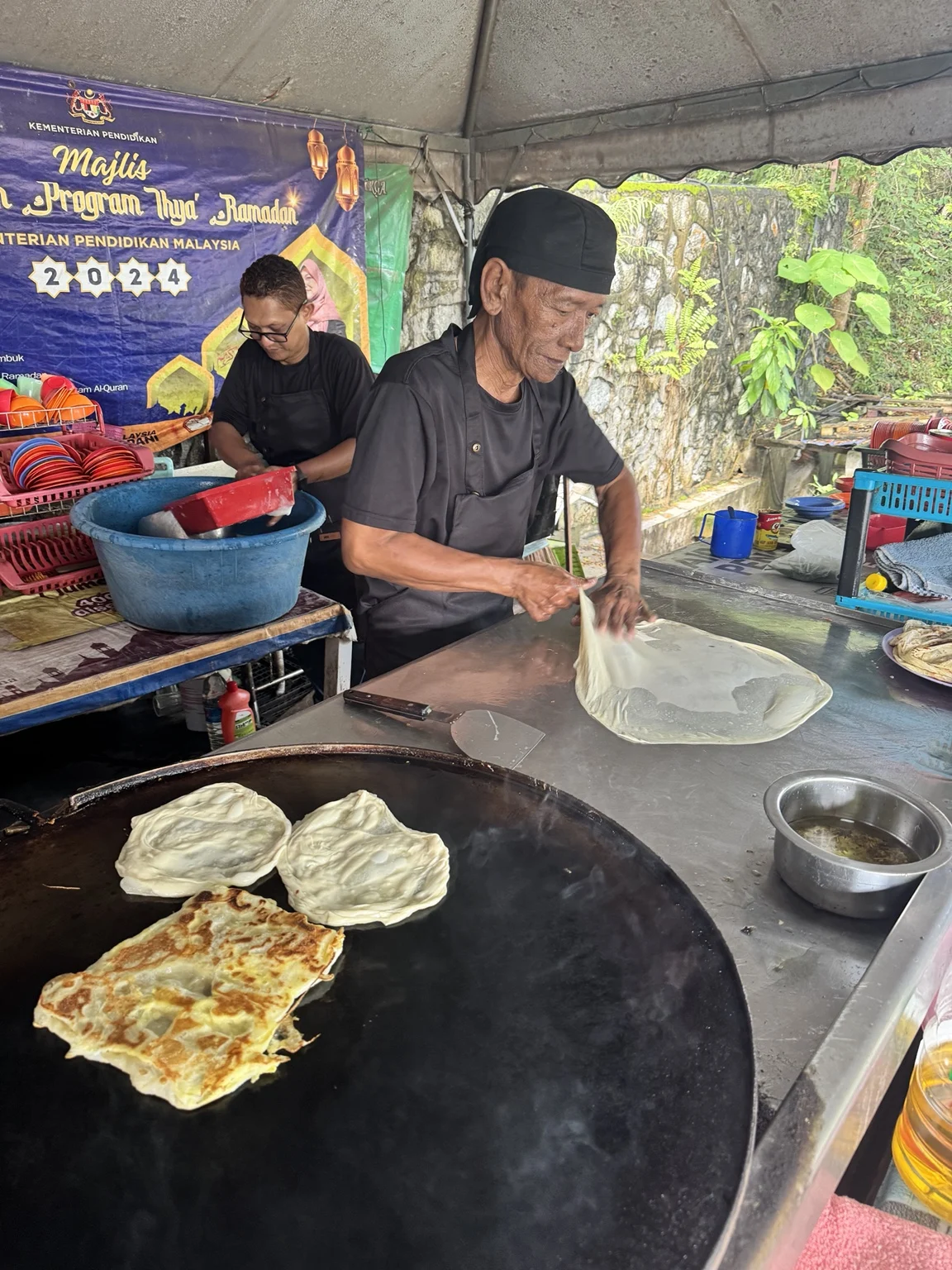 Pak Ude sedang menebar roti canai